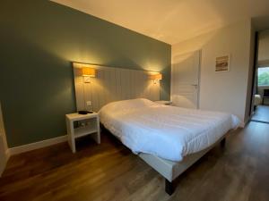 a bedroom with a white bed and a green wall at Le Cabellou - Appt avec piscine commune in Concarneau