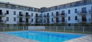 a swimming pool in front of a building at Le Cabellou - Appt avec piscine commune in Concarneau