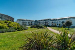an apartment complex with a grassy field in front of a building at Le Cabellou - Appt avec piscine commune in Concarneau