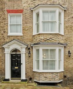 een stenen huis met een zwarte deur en twee ramen bij Old Town House by Ezestays, IN THE HEART OF THE OLD TOWN MARGATE in Margate