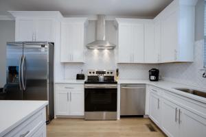a kitchen with white cabinets and a stainless steel refrigerator at Modern Townhome, 10min to Downtown! 8min to Grand Ole Opry! Sleeps 8! in Nashville