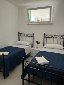 2 Betten in einem Zimmer mit Fenster in der Unterkunft A due passi dal mare in Granitola