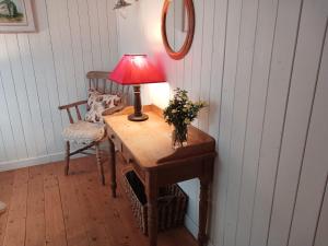 uma mesa com um candeeiro e uma cadeira num quarto em Roberts’ Cottage em Westport