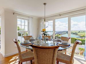 uma sala de jantar com mesa, cadeiras e janelas em 3 Bed in Saint Just in Roseland 81488 em Saint Just in Roseland