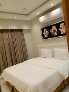 ein Schlafzimmer mit einem weißen Bett in einem Zimmer in der Unterkunft جودي للغرف الفندقية المتميزة in Khobar