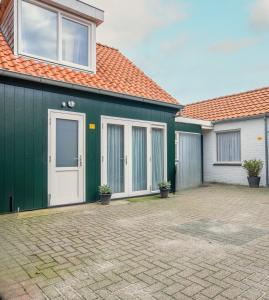a house with a green wall and a driveway at Puur Texels 9a in De Koog