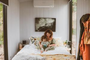 Eine Frau und ein Kind auf einem Bett in der Unterkunft River Ridge Tiny House in South Arm
