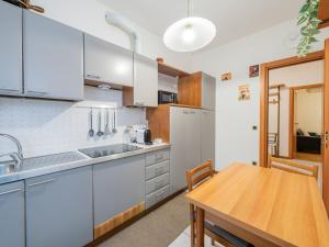 cocina con armarios blancos y mesa de madera en I Host Apartment - Abeti 15 en Baggio