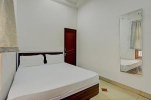 a white bedroom with a bed and a mirror at OYO New dream in Nārnaul