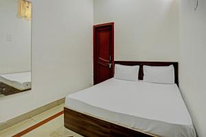 a bedroom with a white bed with a wooden headboard at OYO New dream in Nārnaul