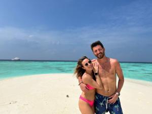 a man and a woman standing on a beach at BY THE SHADE in Hangnaameedhoo