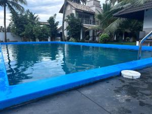 a blue swimming pool in front of a house at Backwater Brook in Kumarakom