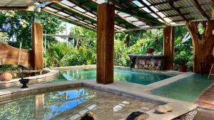 a swimming pool with a pergola and a swimming pool at Arenal Monara in Fortuna
