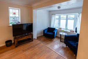 a living room with a flat screen tv and two blue chairs at Fernbanks in Ferndown