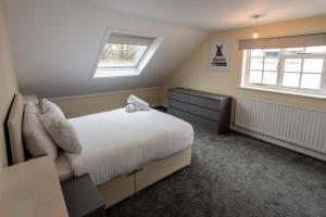 a bedroom with a bed and two windows at Fernbanks in Ferndown