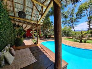 una piscina con pérgola junto a una casa en Champagny Pousada, en Santo Antônio do Pinhal