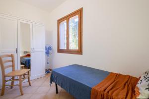 um quarto com uma cama, uma cadeira e uma janela em Rosa's Apartment em Isola Rossa