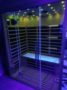 Una ducha a ras de suelo en una habitación con iluminación púrpura. en Virtuel Spa en Achicourt