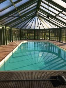 a large swimming pool in a building with a glass ceiling at Domaine de la Haute Justerie - piscine & billard à l’orée des bois - Loire Valley in Fondettes
