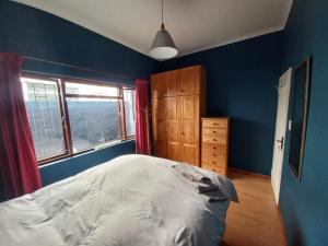 a blue bedroom with a bed and a window at Obz House in Cape Town
