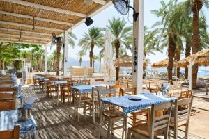 Royal Beach Eilat by Isrotel Exclusive في إيلات: مطعم على الشاطئ به طاولات وكراسي