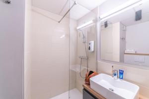 a white bathroom with a sink and a shower at Montempô Appart'Hôtel Bordeaux Centre - Bassins à flot in Bordeaux