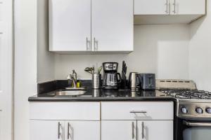 uma cozinha branca com um lavatório e um fogão em Modern NY Style 2BD Apartment in Upper East Side Manhattan em Nova York