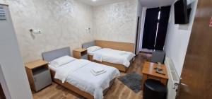 a room with two beds and a desk and a television at Pensiunea Old Sheriff in Bistriţa