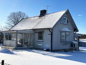 una pequeña casa gris en la nieve con nieve en Cosy cottage located close to a bay in Skappevik, en Bergkvara