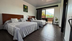 a hotel room with two beds and a balcony at Arenal Monara in Fortuna