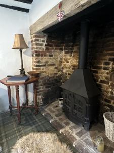 a fireplace in a room with a table and a lamp at Eglantine in Crondall