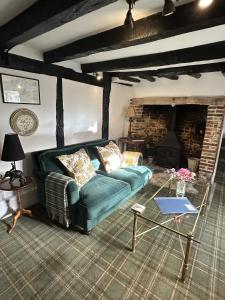 a living room with a green couch and a fireplace at Eglantine in Crondall