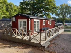 a small red house with a wooden deck at Ursand Resort & Camping in Vänersborg