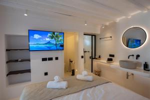 a bedroom with a large bed and a tv on the wall at My Comfy Manto Town Apartment in Mikonos