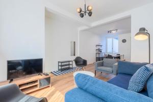 un salon avec un canapé bleu et une télévision dans l'établissement Roubaix - Beautiful 4 bedrooms house with terrace!, à Roubaix