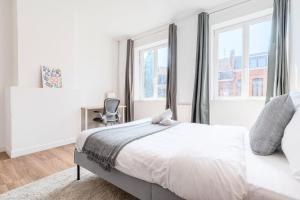 1 dormitorio blanco con 1 cama y 2 ventanas en Roubaix - Beautiful 4 bedrooms house with terrace!, en Roubaix