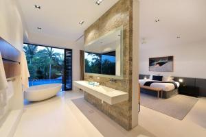 a bathroom with a tub and a bedroom with a bed at 61 Murphy Street - Luxury Holiday Home in Port Douglas