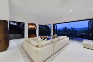 a living room with a white couch and large windows at 61 Murphy Street - Luxury Holiday Home in Port Douglas +23 photos