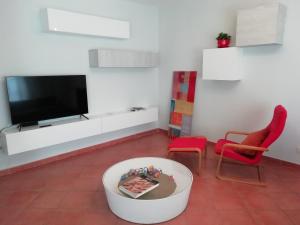 a living room with a tv and a red chair at Casa Arcobaleno in Siena