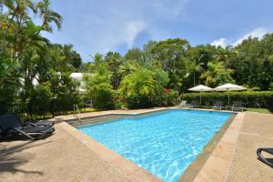 uma piscina com cadeiras e guarda-sóis num quintal em Fairway Vistas - A Group Escape at Mirage Resort em Port Douglas