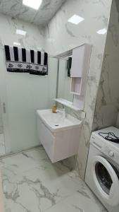 a white bathroom with a sink and a washing machine at Apartment baku in Baku