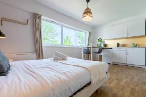 een slaapkamer met een wit bed en een keuken bij Croisé Laroche equipped studio! in Marcq-en-Baroeul