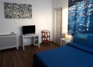 una camera con letto blu e televisore di B&B Stella Marina ad Acitrezza