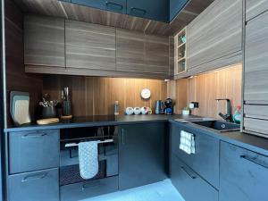 a kitchen with dark blue cabinets and wooden walls at Ground floor central apartment in Kingsbridge