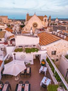 un patio esterno con tavoli, sedie e ombrellone di Hotel Corte Altavilla a Conversano