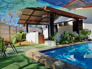 una piscina con pérgola junto a una casa en CASA HALI, en Puntarenas