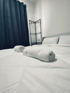 Comfy suites في Donggongon: سريرين بيض وعليهم مناشف في غرفة النوم
