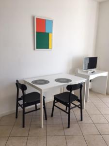 a white table with two chairs and a desk with a computer at flat in Padova center in Padova