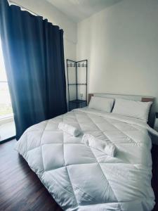 ein weißes Bett mit Kissen darauf im Schlafzimmer in der Unterkunft Comfy suites in Donggongon