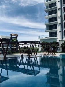 a pool with a wooden bridge in front of a building at Comfy suites in Donggongon